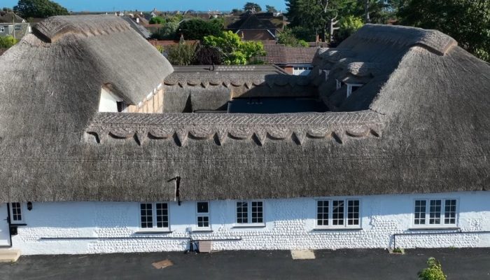 Image shows a drone shot of the exterior of a Residential Development in Ferring. The building has a thatch roof and a courtyard in the center